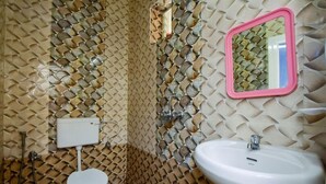 A bathroom with a patterned tile wall, a toilet, a sink, and a mirror. - ronz vis da praia (Calangute)
