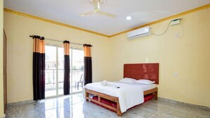A hotel room with a bed, a ceiling fan, an air conditioning unit, and a sliding glass door to the outside. - ronz vis da praia (Calangute)