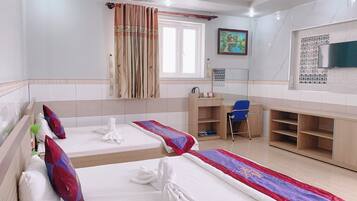 A hotel room with two beds, a desk, a chair, a television, and a window with curtains.