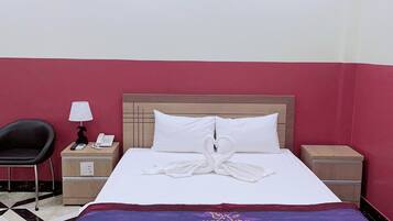 A hotel room with a bed, a nightstand, a chair, and a tiled floor.