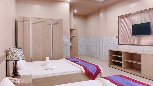 Une chambre d’hôtel avec deux lits, une armoire, une télévision et un mini-bar.