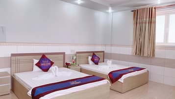 Ein Hotelzimmer mit zwei Betten, jeweils mit Kopfstütze, Nachttisch und Telefon. Das Zimmer verfügt über ein Fenster mit Vorhängen, eine Wand mit Fliesen und eine Deckenleuchte.