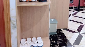 Une étagère en bois avec des compartiments de rangement, une bouilloire, une tasse et une paire de chaussons.