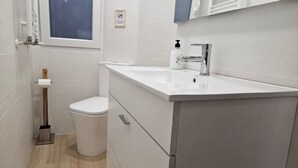 Une salle de bain moderne équipée de toilettes, d’un lavabo et d’un meuble de rangement.