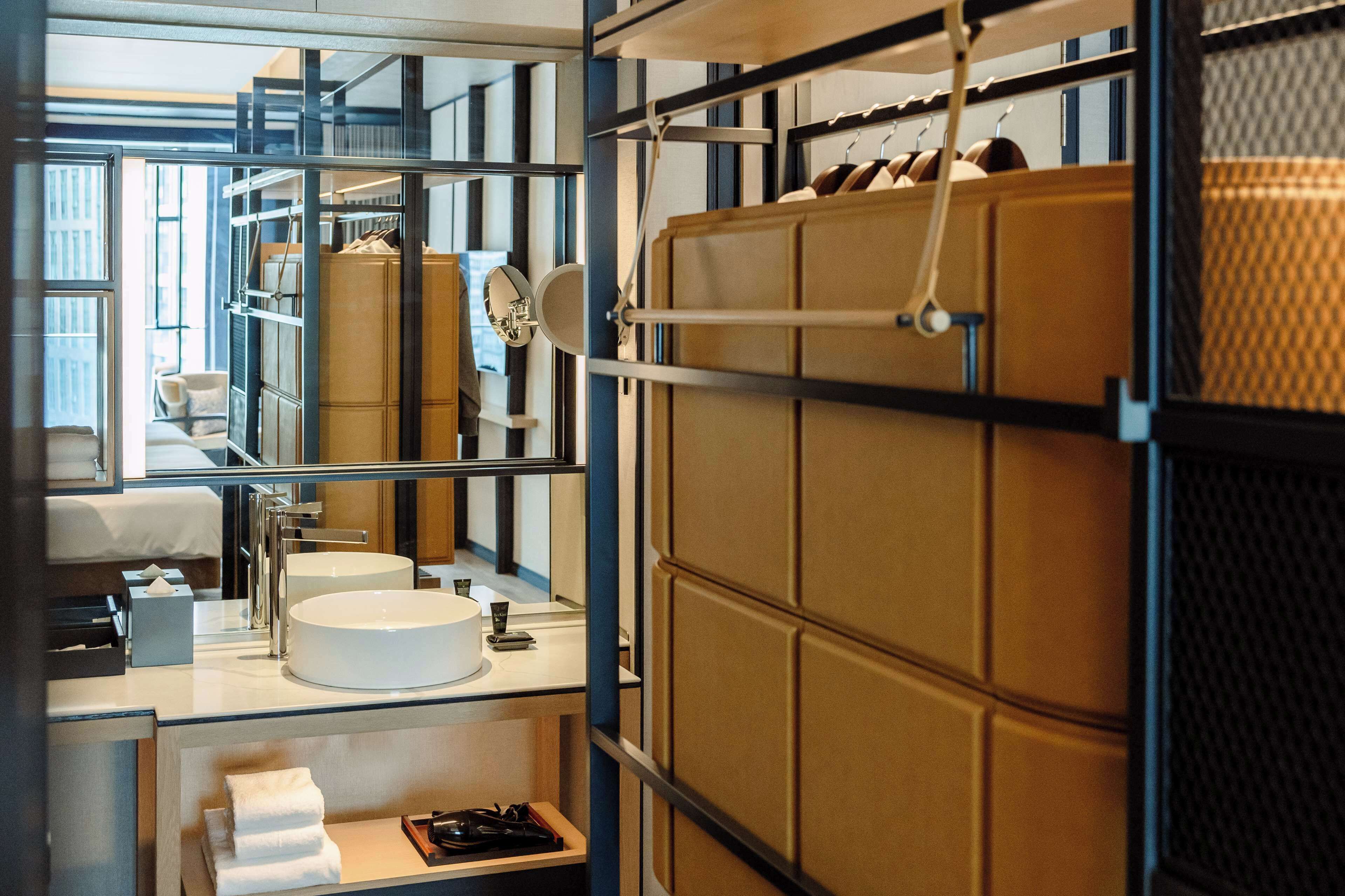 A modern bathroom with a large mirror, a round sink, and a towel rack.