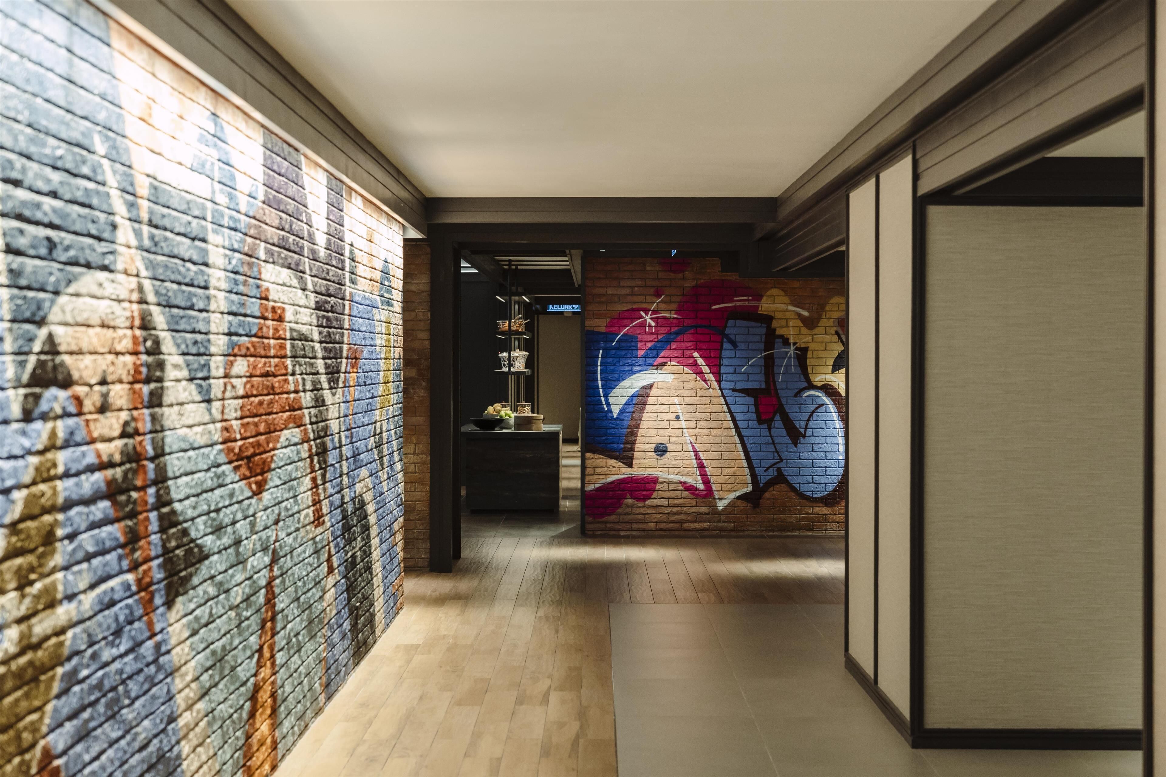 A hallway with a brick wall on the left and a colorful mural on the right.