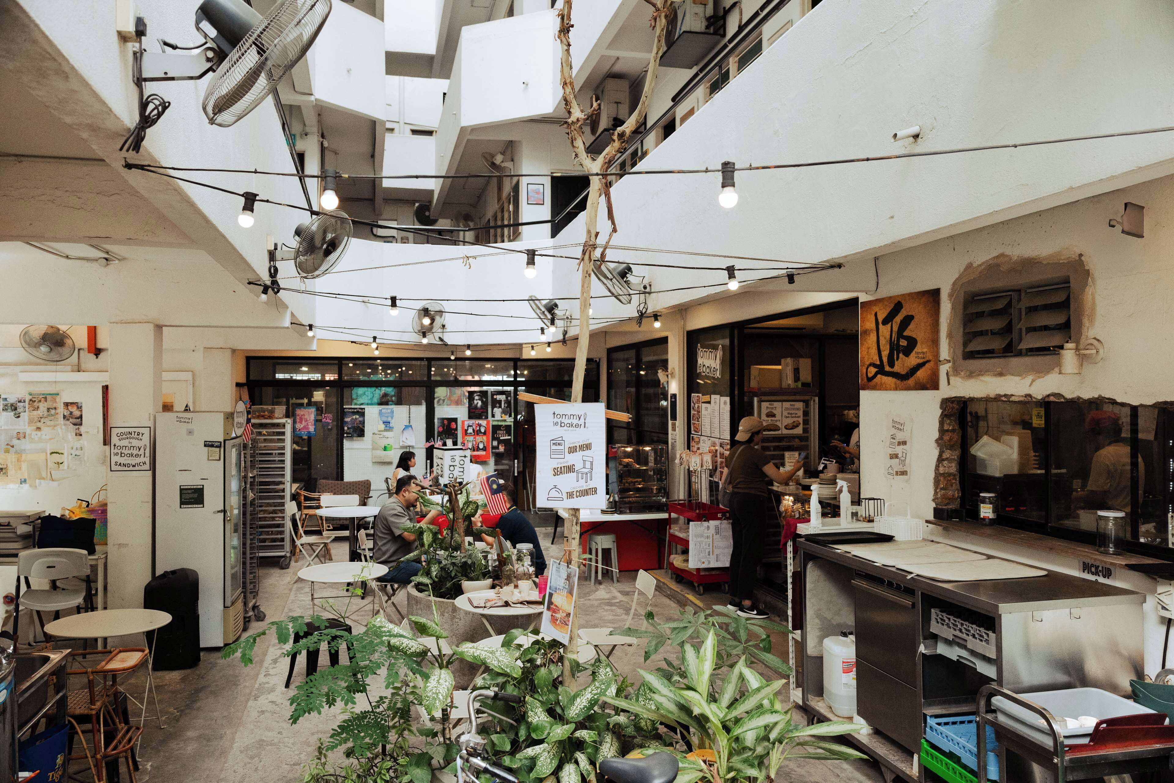 L’intérieur d’un restaurant présente plusieurs espaces de restauration, un comptoir et une cuisine visible.