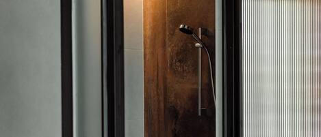 A modern bathroom with a wooden vanity, a shower with a handheld showerhead, and a toilet.