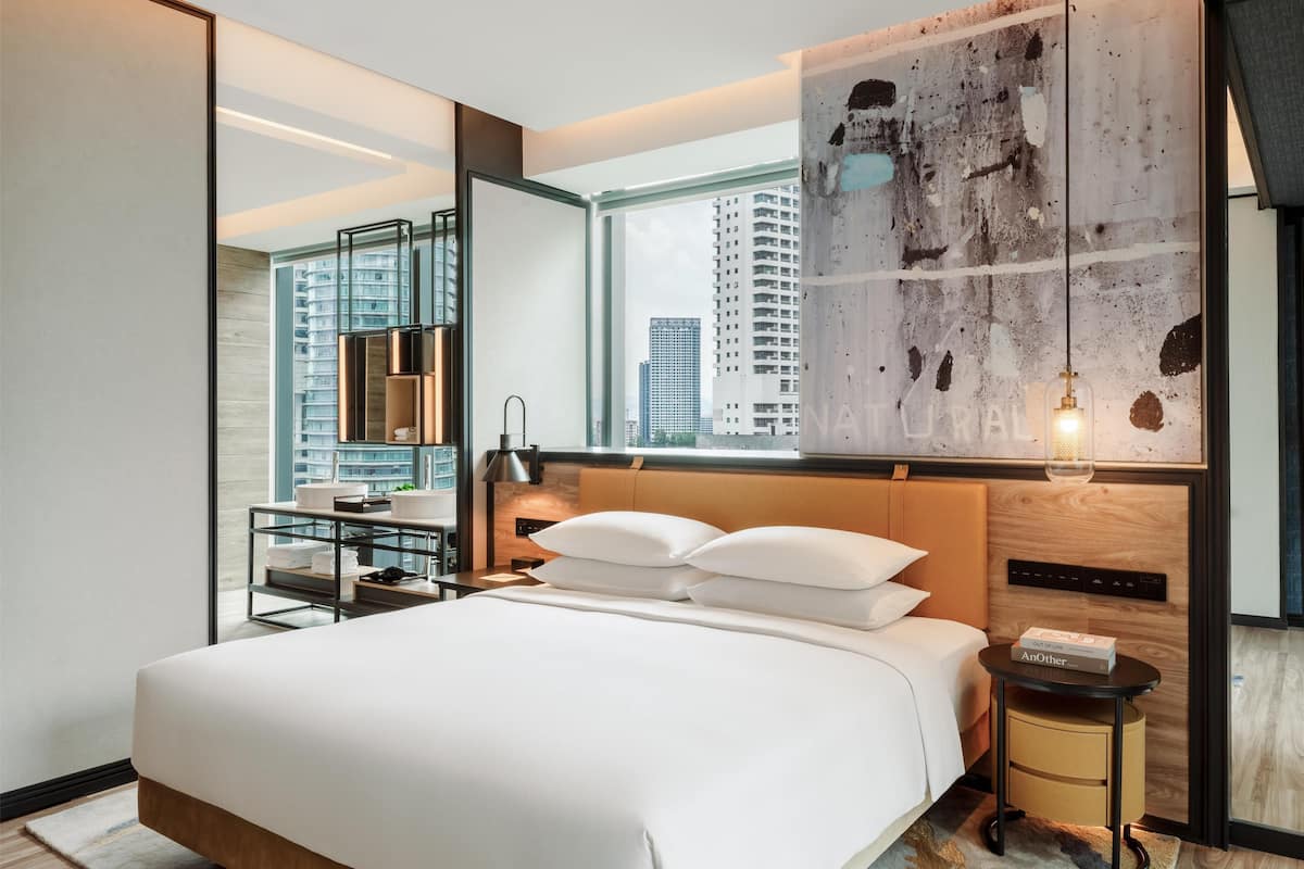 A modern hotel room with a large bed, a view of the city, and a minimalist decor.