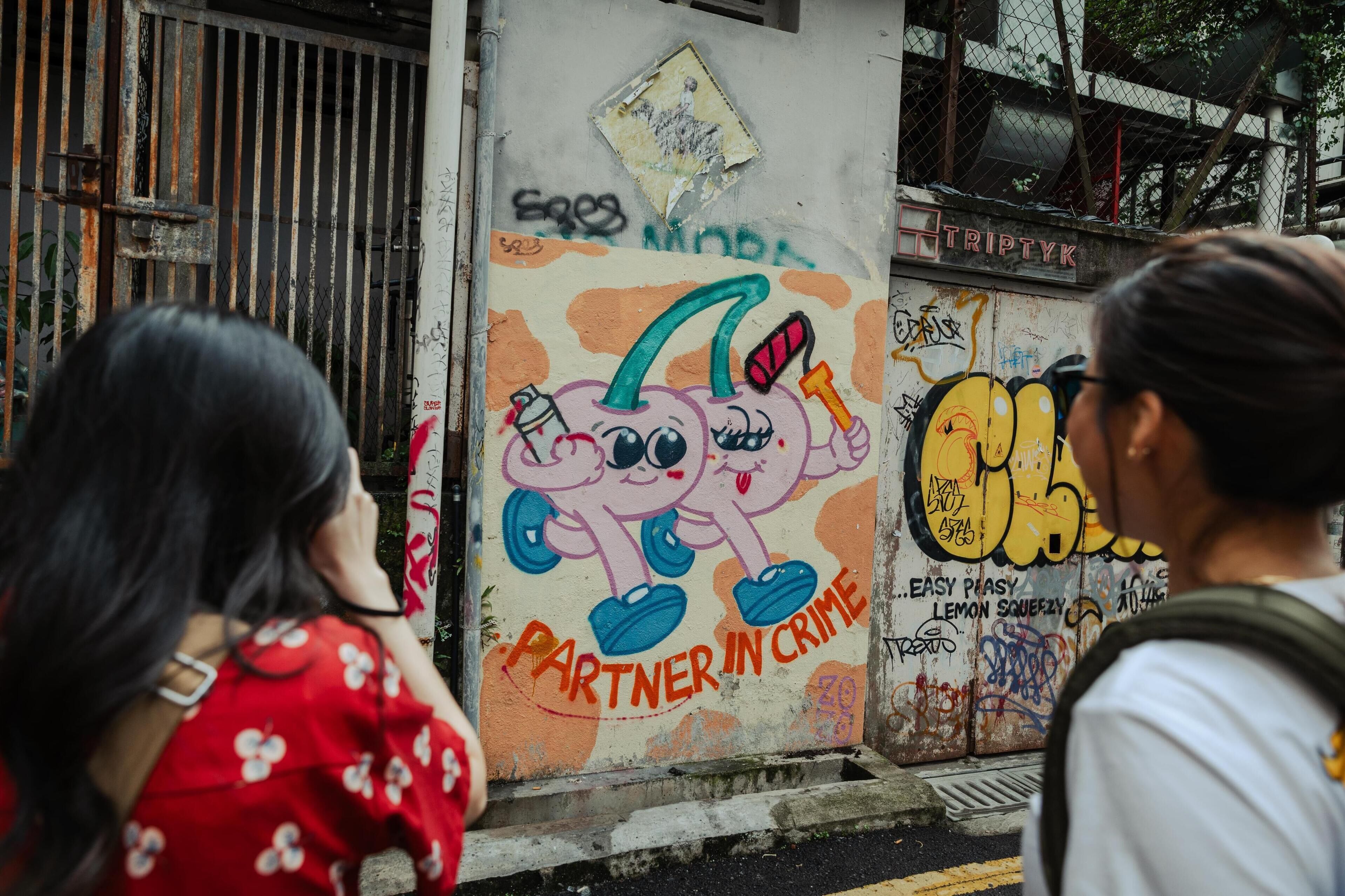 A wall with colorful graffiti and text, including 'PARTNER IN CRIME' and 'EASY PIAS LEMON SQUEEZY'.