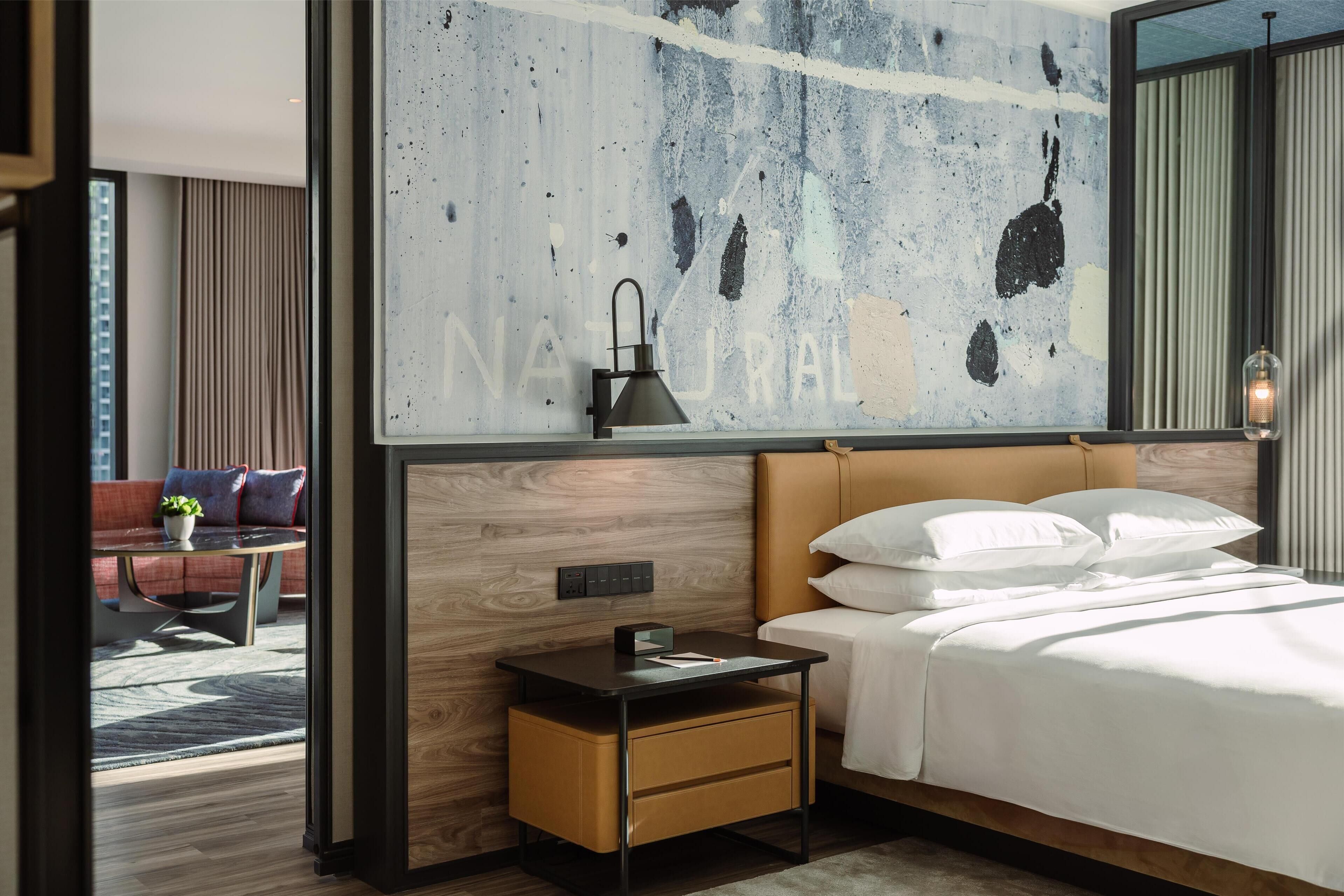 Une chambre d’hôtel moderne dotée d’un grand lit, d’une table de chevet, d’un bureau et offrant une vue sur le paysage urbain.