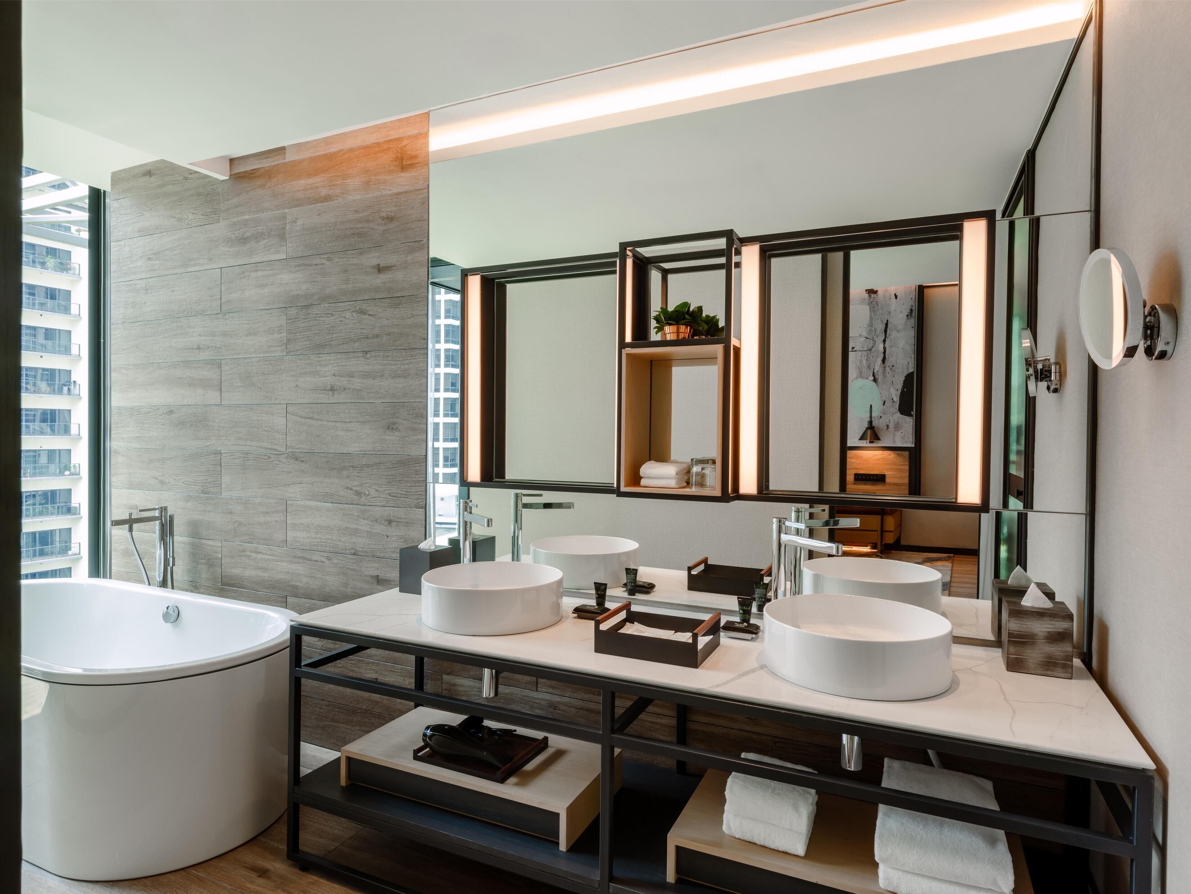 Un baño moderno con una bañera grande, dos lavamanos y un espejo con iluminación integrada.