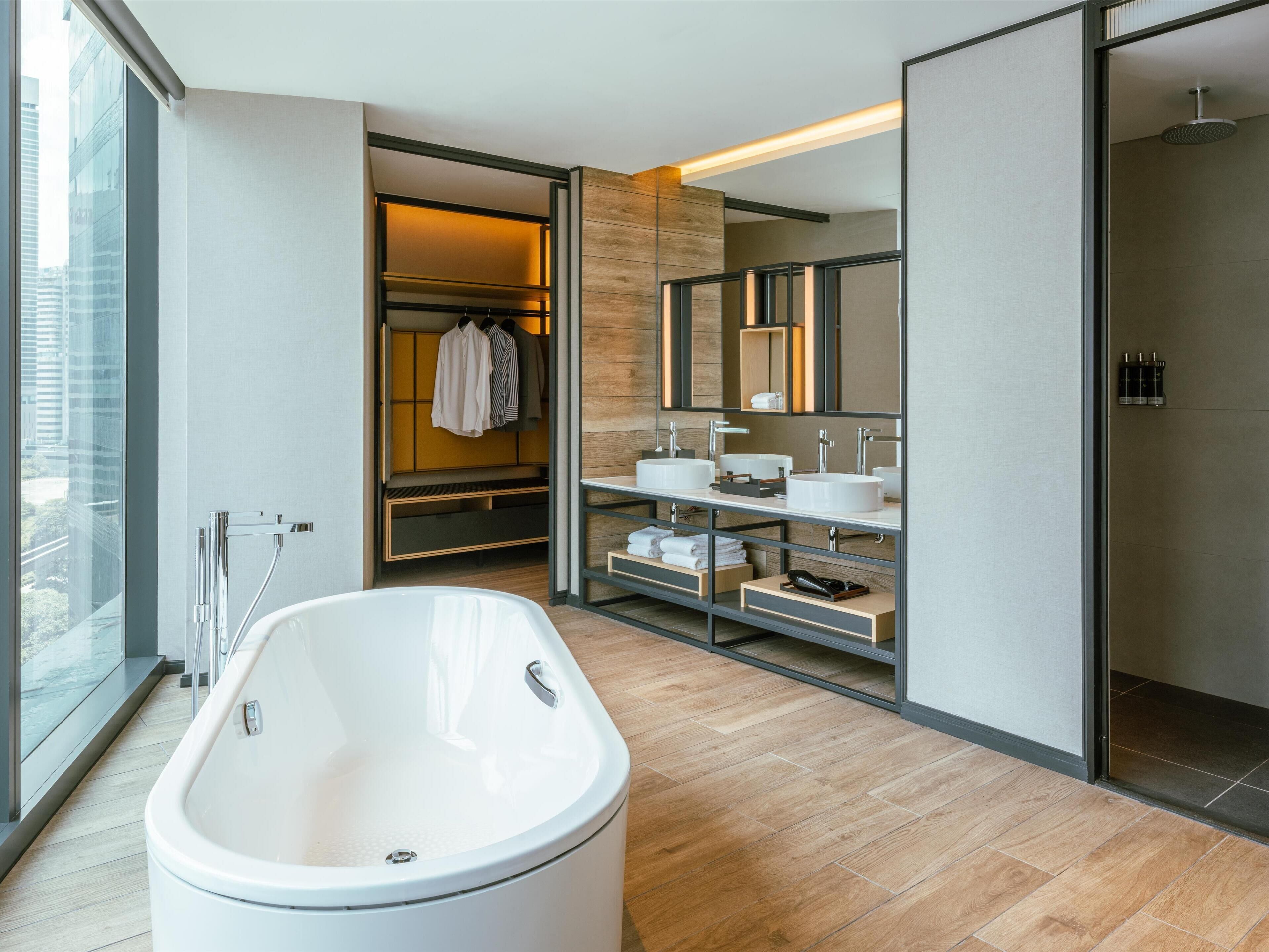 A modern bathroom with a freestanding bathtub, built-in vanity with two sinks, and a walk-in shower.