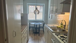 A kitchen with a dining table, chairs, a gas stove, and a window with blinds.