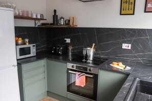 Cocina equipada con microondas, tostadora, horno y salpicadero de mármol.