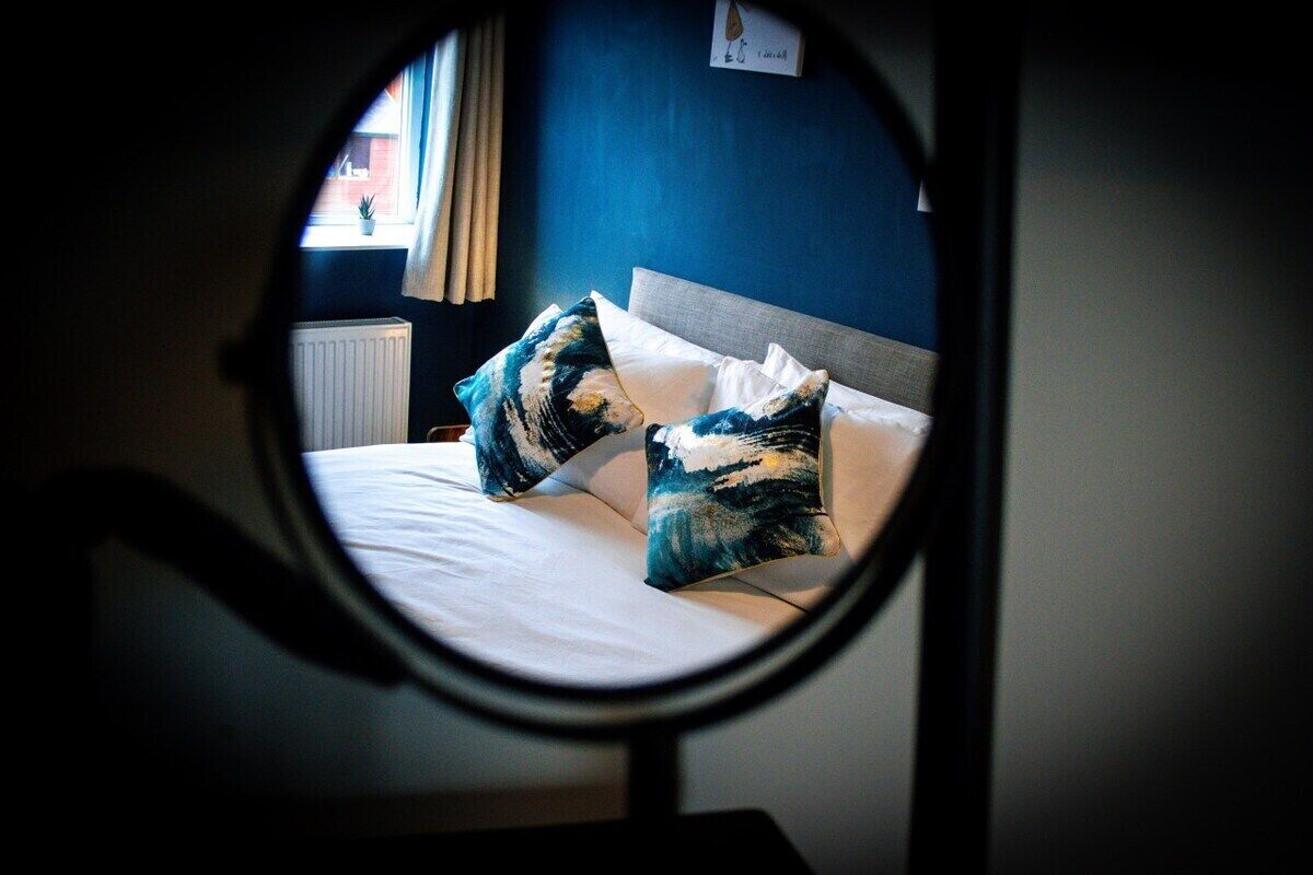A bed with a headboard, two pillows, and a window with curtains.