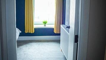 A narrow hallway with a window, yellow curtains, and a radiator.