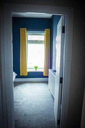A narrow hallway with a window, yellow curtains, and a radiator.