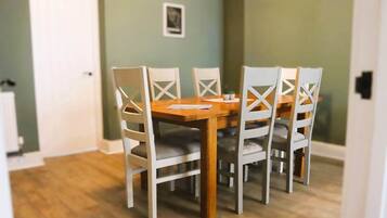 A dining area with a wooden table and white chairs with cross-back designs.
