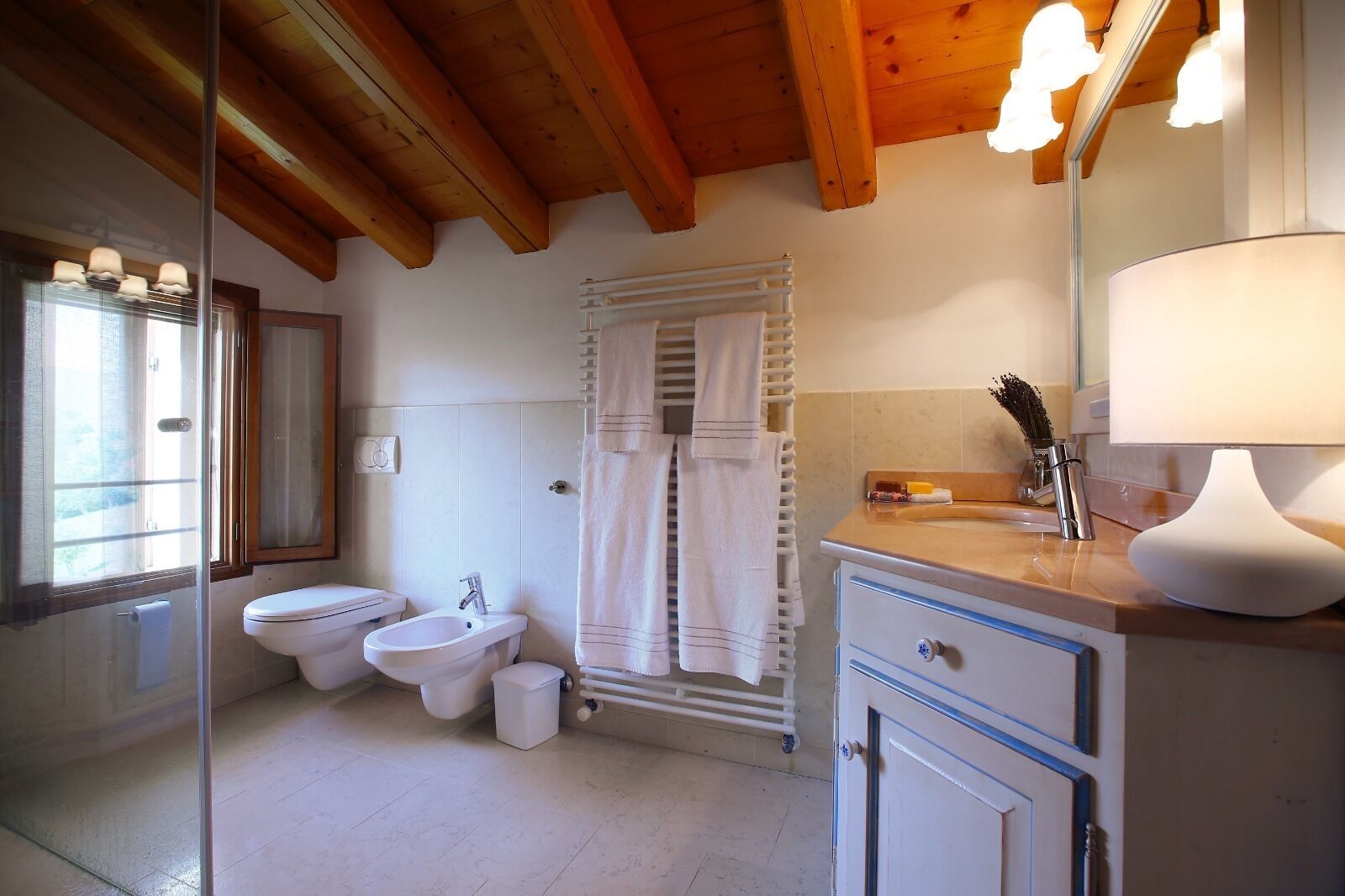 Un baño con dos inodoros, un bidé, un lavabo, un espejo y un perchero para toallas.