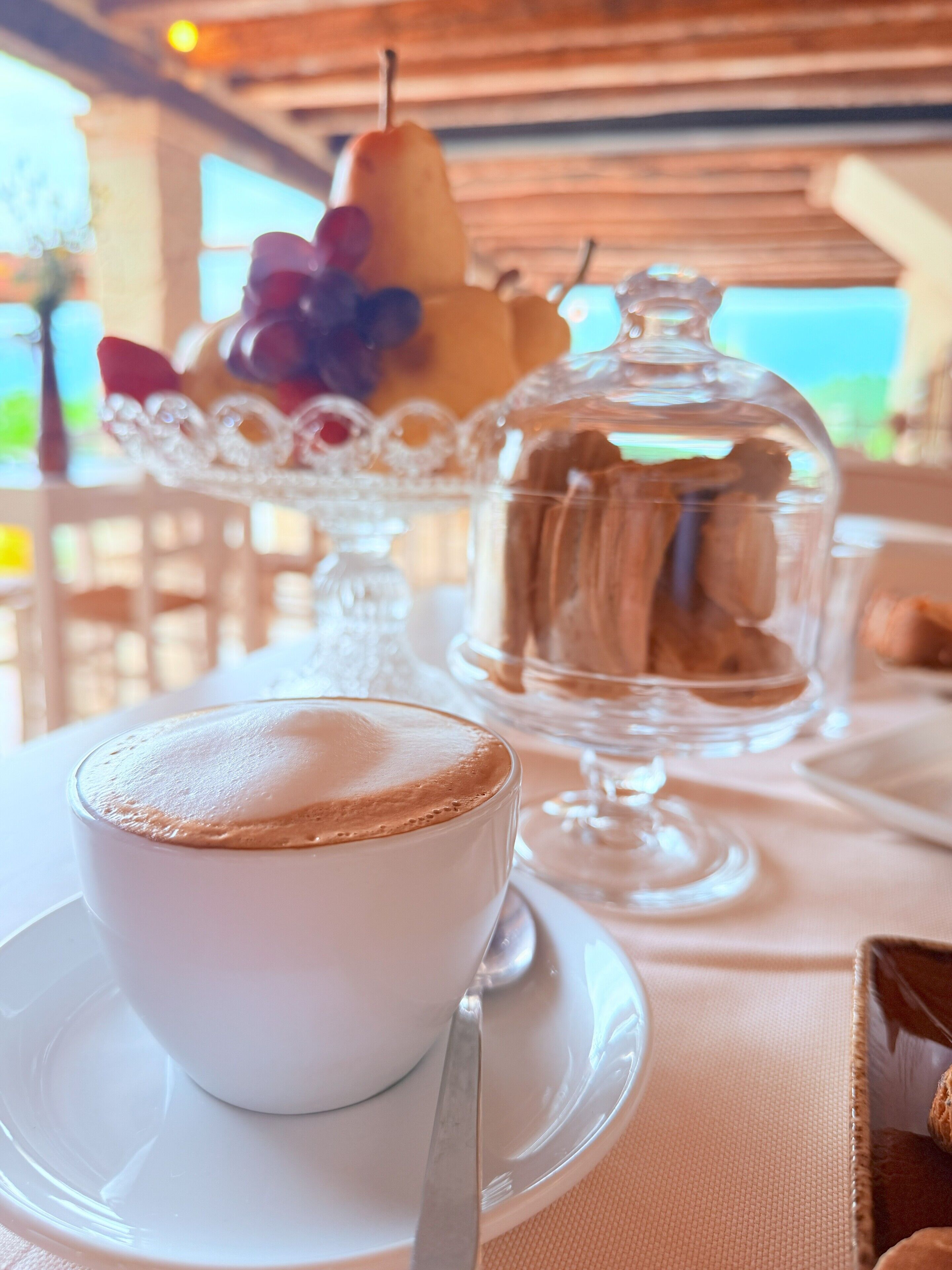 A table with a cup of coffee, a glass of water, a pear, and a glass of wine.