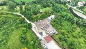 Une vue aérienne d’une propriété rurale comprenant une grande maison, des champs adjacents et un petit bâtiment indépendant.