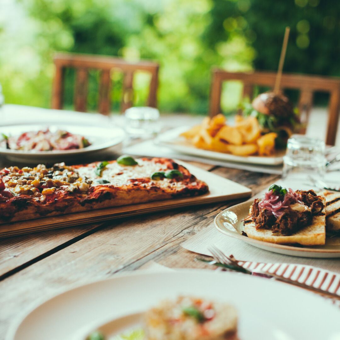 A wooden table with various dishes including pizza, fries, and a sandwich.