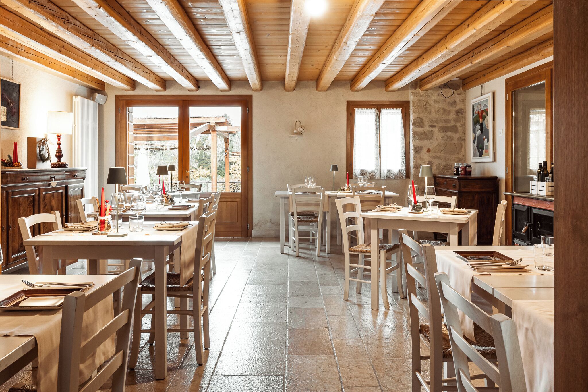 A dining area with wooden tables and chairs, stone walls, and a view of the outdoors.