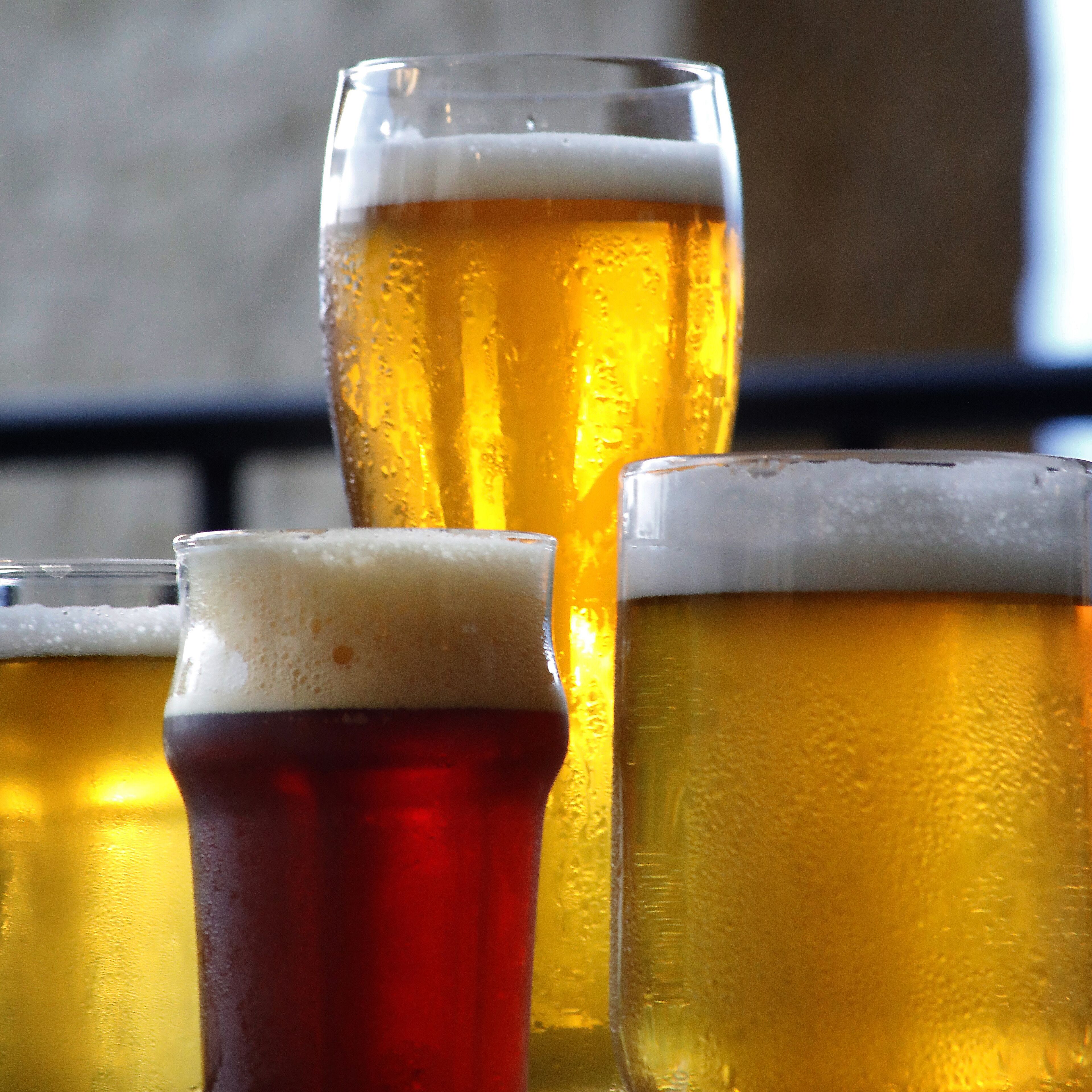 Four glasses of beer with varying colors and foam levels.