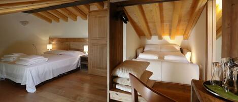A room with two beds, wooden beams, a wooden chair, and a table with glasses.