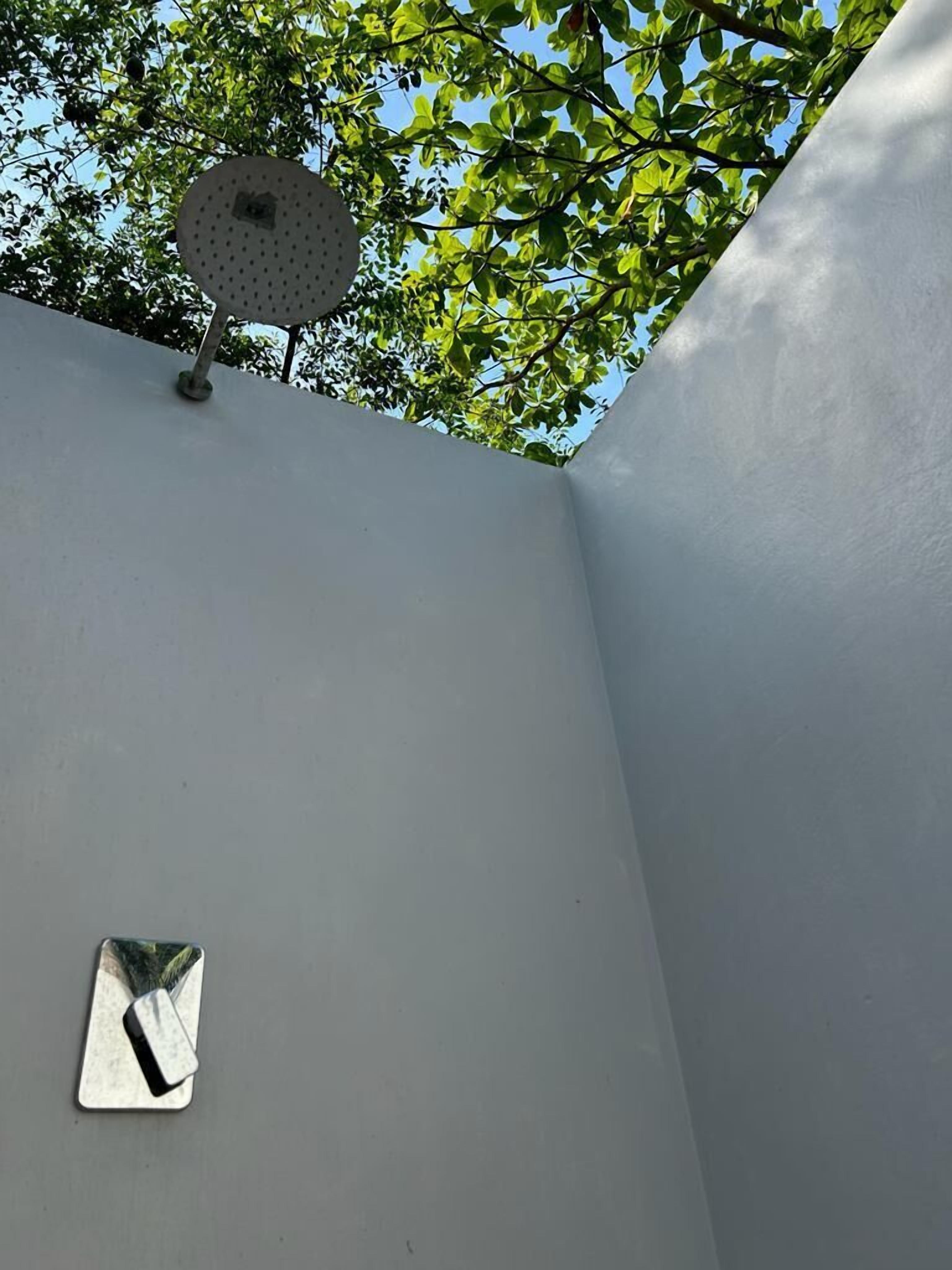 Pared branca com um pequeno espelho retangular e um ventilador de teto.