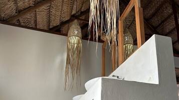 Un baño con inodoro blanco, un tapete tejido en el suelo y una lámpara colgante.