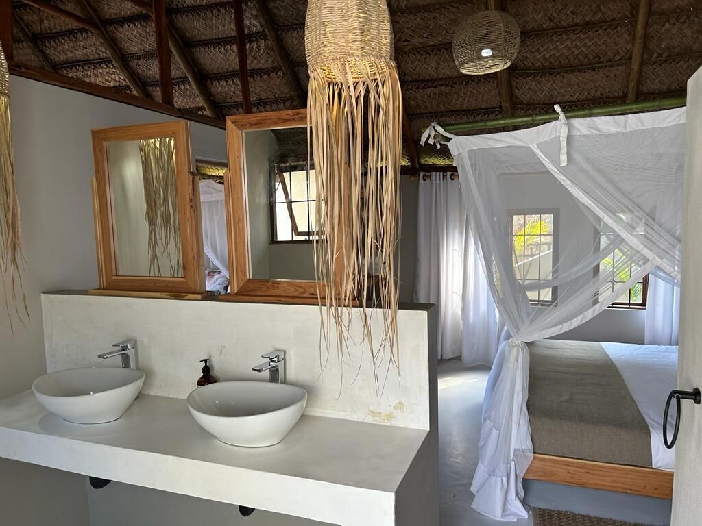 Un baño con dos lavamanos, un espejo y una cama con dosel.
