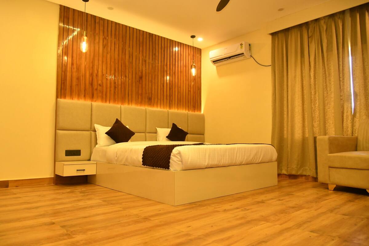 A modern bedroom with a large bed, a nightstand, a chair, and a wooden accent wall.