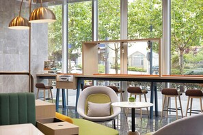 A modern cafe interior with a bar area, seating, and large windows offering a view of the street.