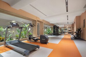 Un gimnasio con cintas de correr, bicicletas estáticas y máquinas de pesas.