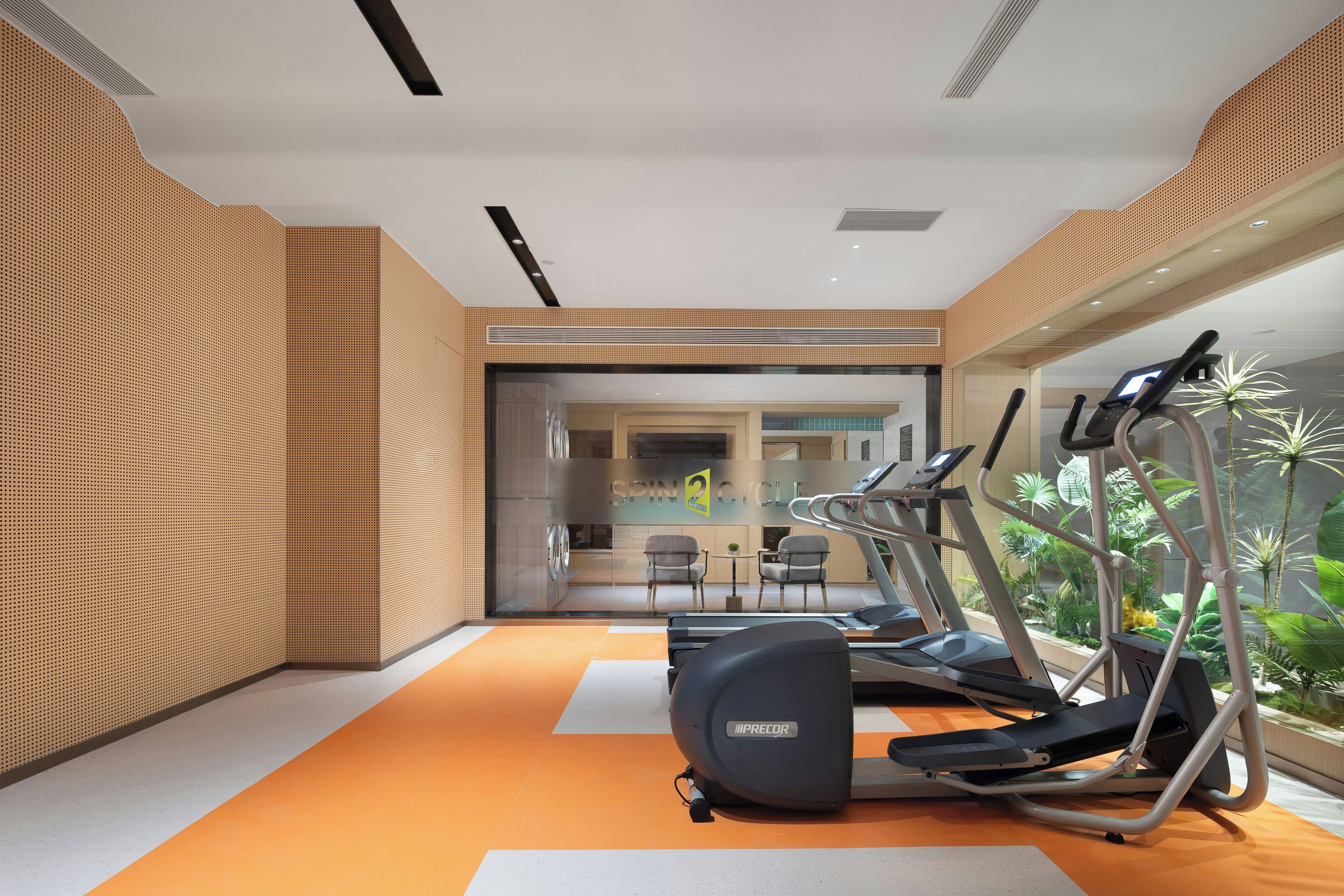 A gym with treadmills, stationary bikes, and a wall with a perforated pattern.