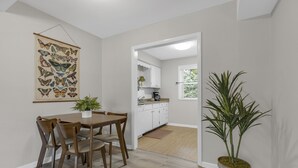 A dining area with a wooden table and chairs, a potted plant, and a butterfly wall art piece.