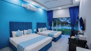 Quarto de hotel com duas camas, uma escrivaninha, uma cadeira, televisão e janela com cortinas.