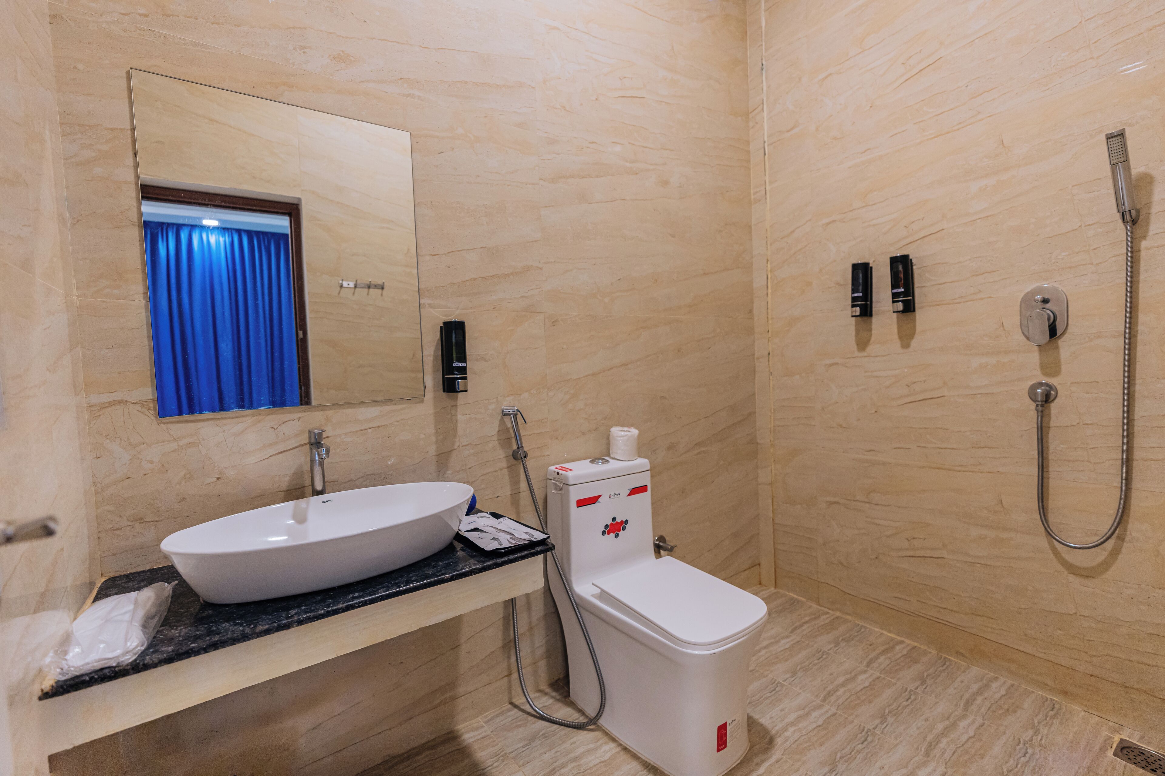 Baño con lavamanos, espejo, inodoro y ducha.