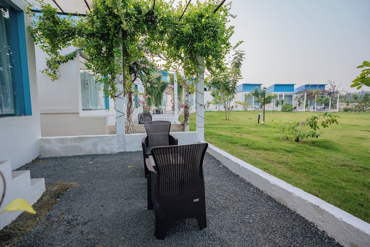 A courtyard with outdoor seating, a pergola with climbing plants, and a view of the hotel buildings in the background.
