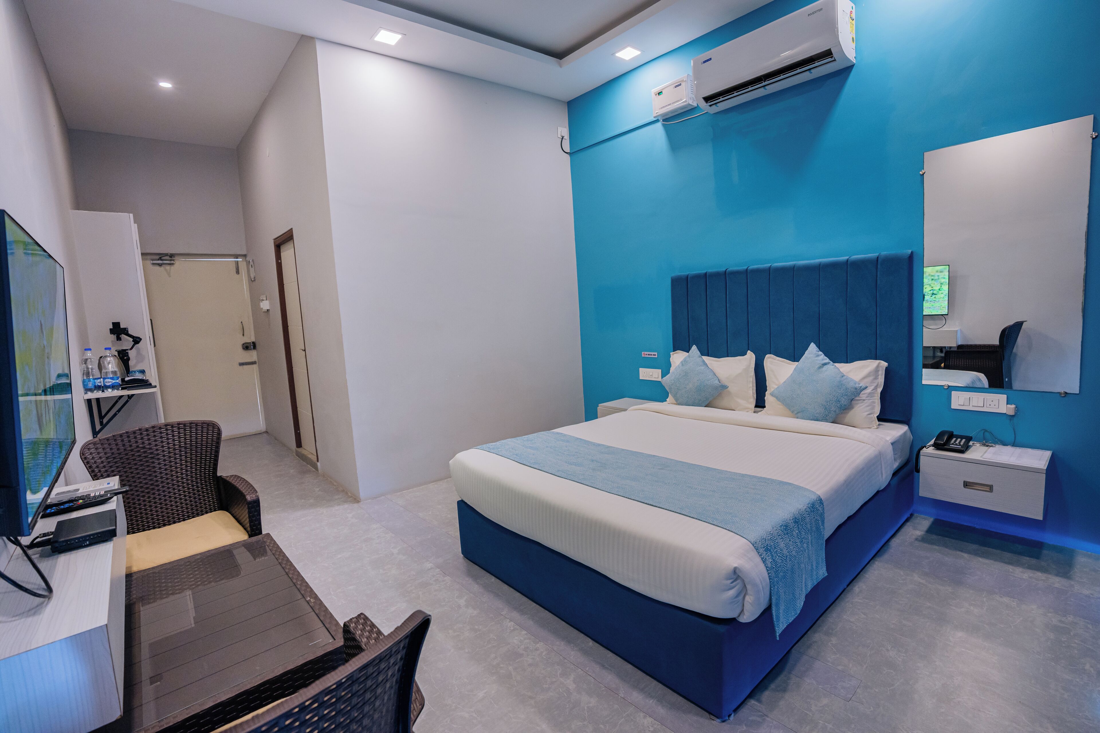 Een moderne hotelkamer met een groot bed, een bureau met een computer, een stoel en een televisie.
