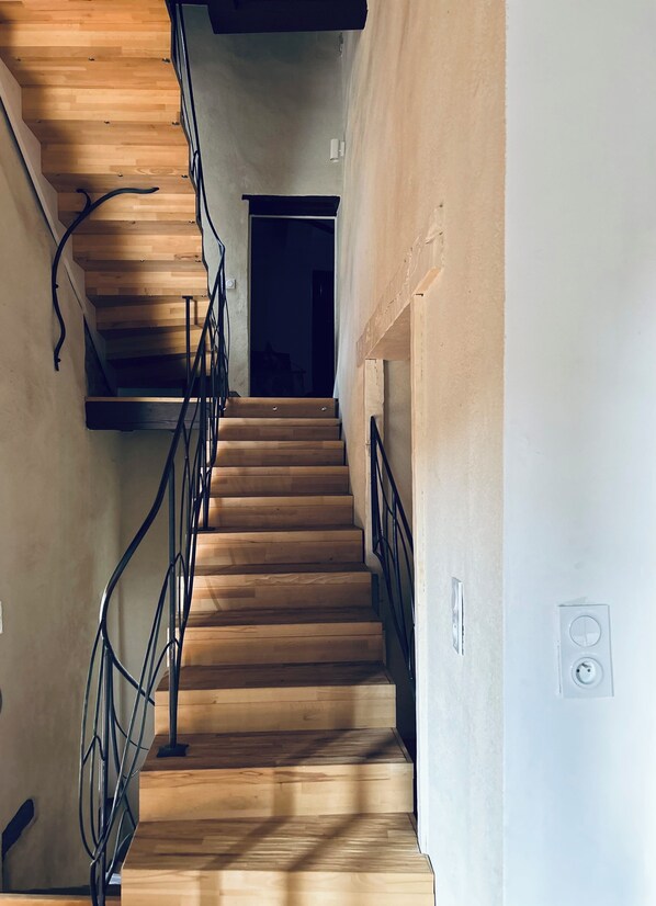 A wooden staircase with metal railings leading to a dark doorway.