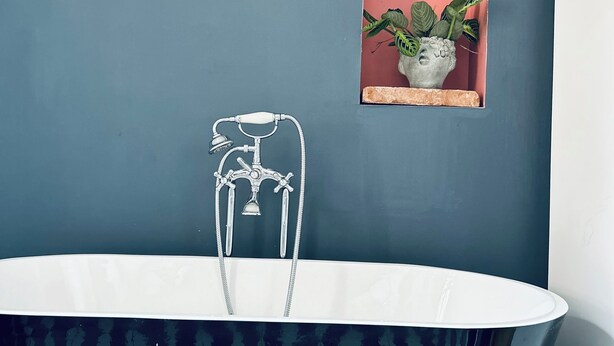 A bathroom with a freestanding bathtub, a small shelf with a plant, and a wall-mounted faucet. - La Maison du Prévôt, au Pied de la Cathédrale ! (Albi)