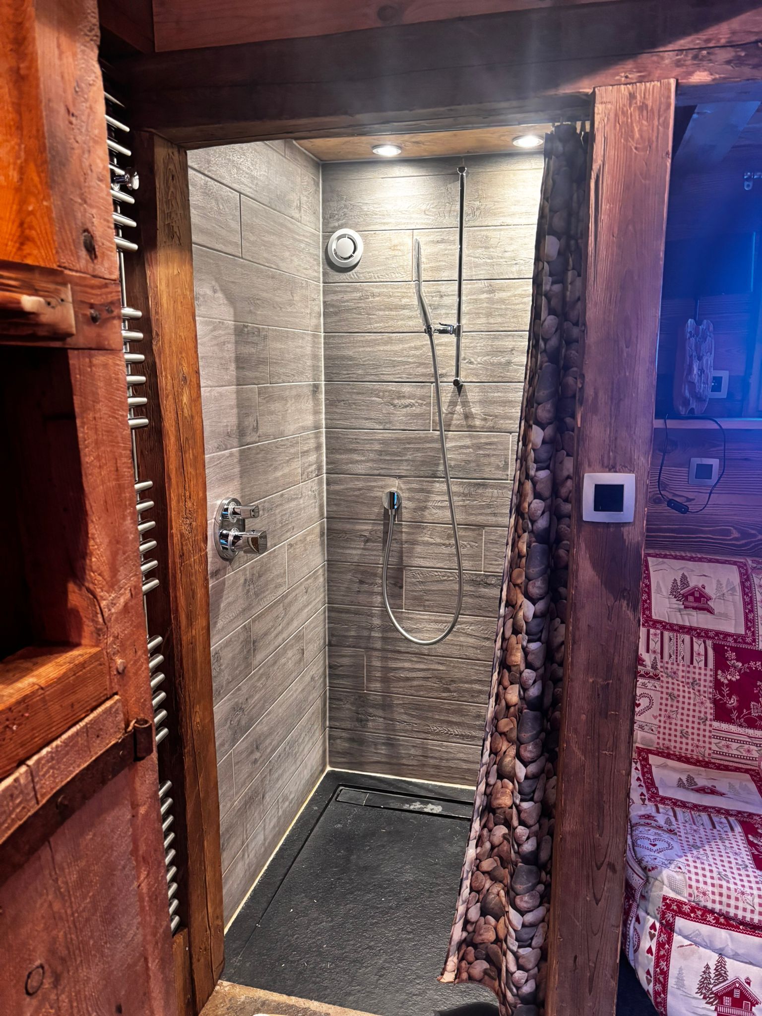 Eine Dusche mit Holzrahmen, einer Steinwand und einem gefliesten Boden.