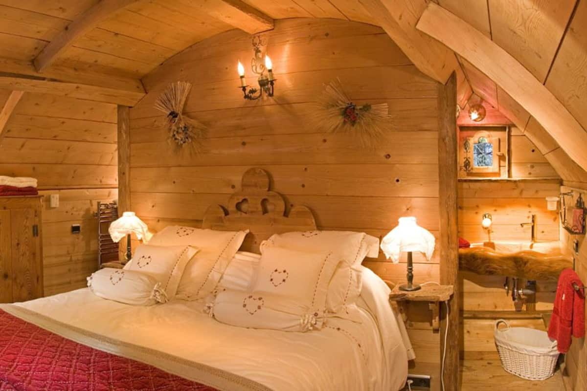 Camera da letto accogliente in legno con un letto, due comodini, un armadio in legno e una piccola finestra.