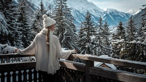 A person sitting on a wooden bench overlooking a snowy mountainous landscape. - Hôtel Les Chalets de Philippe avec Jacuzzis privatifs (Chamonix-Mont-Blanc)