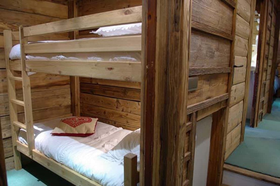 Una cama litera con estructura de madera y ropa de cama blanca.