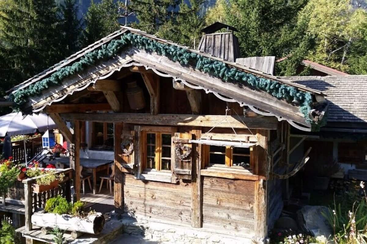 Una baita di legno con un balcone, immersa tra gli alberi.