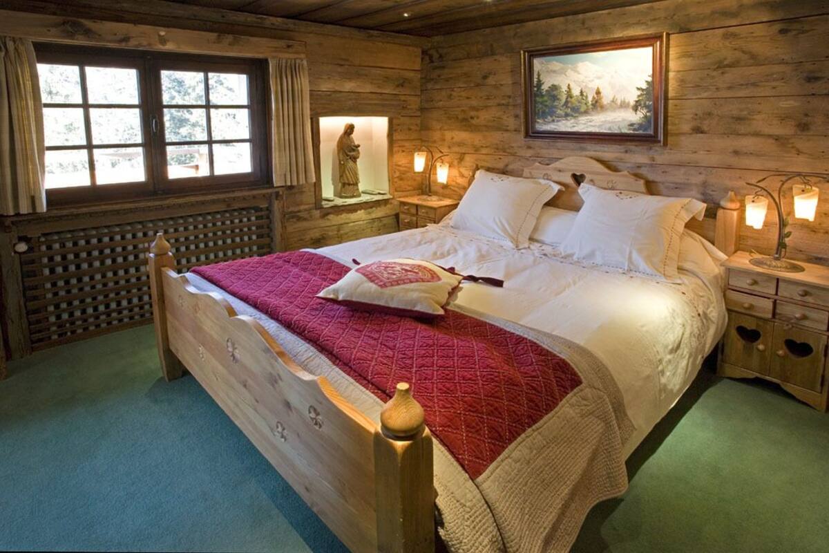 Camera da letto in legno con un letto, comodini e una finestra vista alberi.